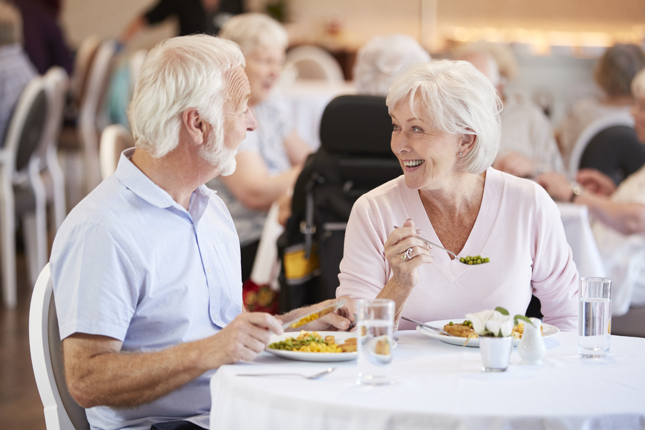 Male and female senior living residents enjoying a meal in the Traditions at Hunter Station community dining room