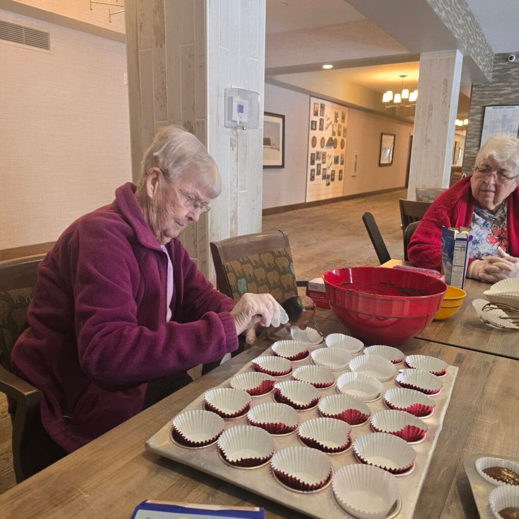 Resident preparing cupcakes during a baking activity at Traditions at Hunter Station